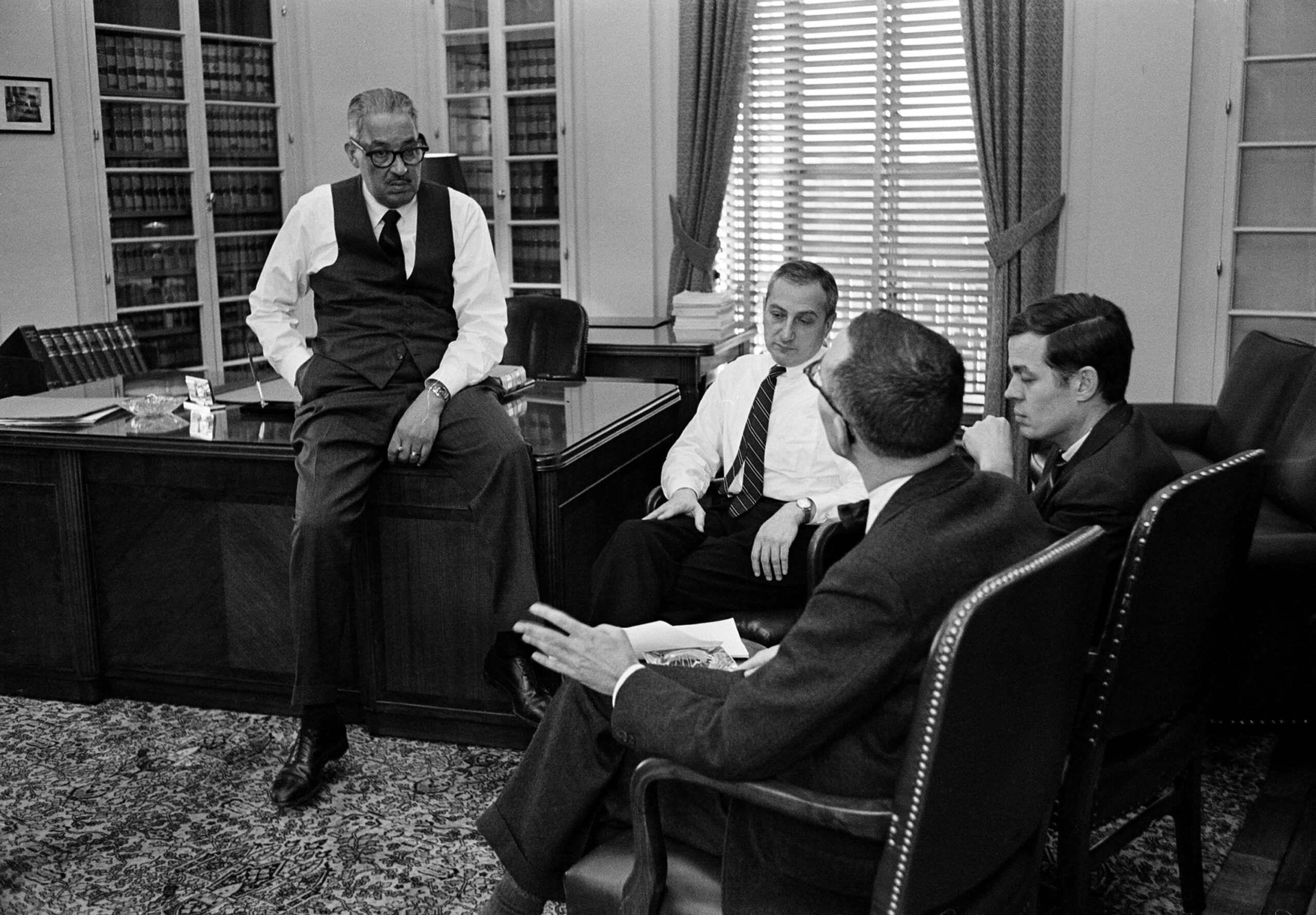 Thurgood Marshall, solicitor general of the United States, sits on the edge of his desk as he confers with three aides in his Department of Justice office in Washington, December 9, 1965. The aides are, from left: Ralph S. Spitzer, first assistant, Louis F. Claiborne, and Daniel M. Friedman, second assistant. (AP Photo)

